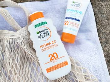 Ambre Solaire Sonnenschutzprodukte lieben im Sand auf einem Handtuch